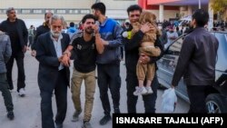 People injured in the explosions are helped outside a hospital in the southern Iranian city of Kerman on January 3.