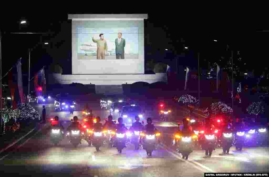 A joint limousine motorcade snakes through the capital decorated with Russian flags and pictures of Putin.  