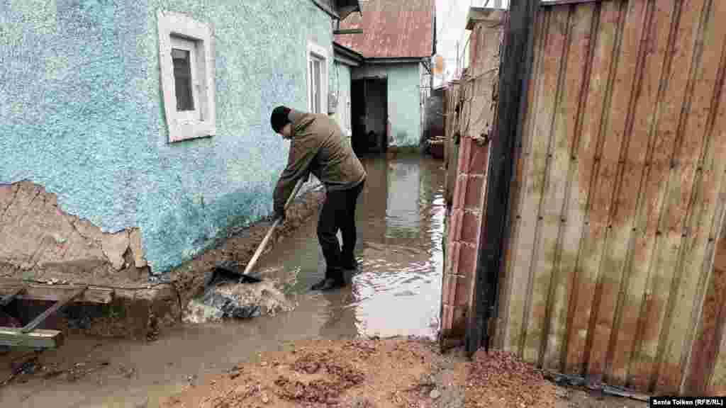 A villager clears muck near his home in Koyandy, a village some 20 kilometers northeast of the nation's capital, Astana. Residents of Koyandy took to the streets and barricaded the roads, furious at the authorities' inability to prepare for the seasonal floods. 