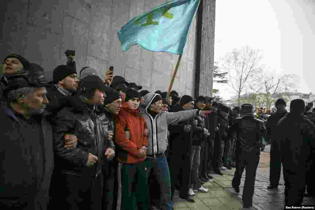 Крымские татары держат флаг своего народа во время митинга у парламента Крыма в Симферополе, 26 февраля 2014 года. Неделей ранее крымский политик поднял вопрос о возможности «отсоединения» полуострова от Украины. Протестующие на Майдане в Киеве в то время находились в процессе отстранения от власти пророссийского президента Виктора Януковича, позже эти протесты стали называть «революцией достоинства».  