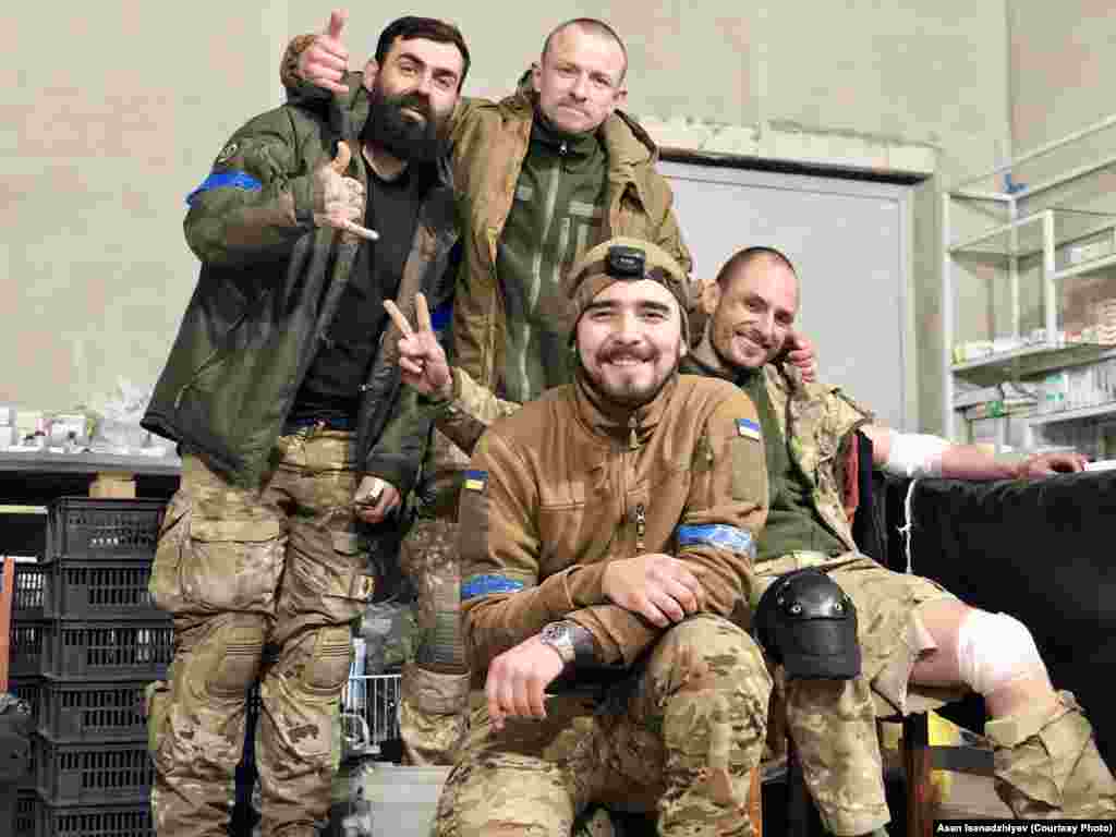Мариуполь, 2022 год. В центре на этом снимке – крымчанин, боевой медик Асан Исенаджиев, предоставивший Радіо Свобода эти фотографии. Он вышел с «Азовстали» в мае 2022 года с последними украинскими подразделениями, которые оставались на окруженном российскими войсками заводе. После этого он  вместе с другими бойцами был заключен в колонии в Еленовке и выжил во время подрыва барака с пленными. 31 декабря 2022 года Асана обменяли. С ним на этой фотографии позируют бойцы «Вишня», «Шпрот» и «Грян» (слева направо). Они прорвались в окруженный Мариуполь на вертолетах. Из них троих в живых остался только «Вишня» – он также прошел российский плен, а после обмена вернулся в армию. «Шпрот» и «Грян» погибли в Мариуполе весной 2022 года