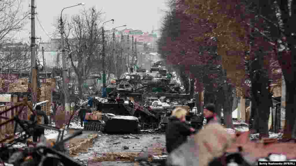 Civilians look at a destroyed Russian armored column in Bucha, near Kyiv, on March 1, 2022. The town was finally captured by Russian troops days after this photo was taken, but they withdrew less than a month later. Following Moscow’s retreat, evidence of war crimes emerged in Bucha, drawing international condemnation.