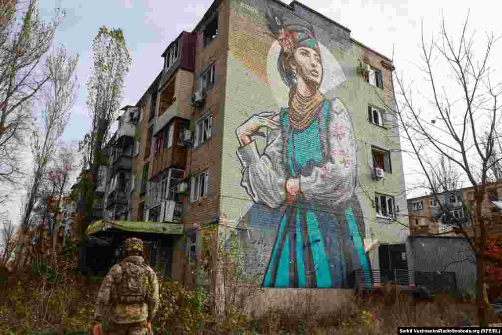 A soldier walks beneath a mural in the embattled town of Avdiyivka in the Donetsk Region in November 2023. 