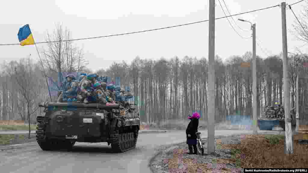 Сльози вдячності. Жінка вітає воїнів ЗСУ, які під державними прапорами рухаються звільненим від окупантів населеним пунктом.  