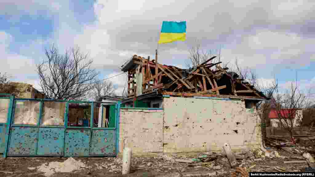 Селище Лук'янівка одразу після звільнення від російських окупантів. Над зруйнованою цивільною будівлею та посіченим кулями двором майорить прапор України. Київщина. Кінець березня 2022 року.