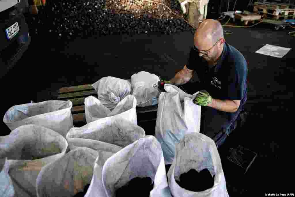 A worker fills bags with coal at Hans Engelke Energie, a&nbsp;heating products company,&nbsp;in Berlin on August 10.&nbsp; In August, the head of Hans Engelke Energie told AFP new customers had arrived en masse this year for cheap coal and wood products and that he had postponed his holidays to keep up with demand. &ldquo;Those who heat with gas but who still have a [coal-burning] stove at home now all want to have coal,&rdquo; he said.&nbsp;