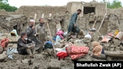 An Afghan family looks at their house, which was destroyed by heavy flooding in the east of the country.