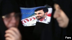Women stand in front of a poster of Mahmud Ahmadenijad. Reformists fear a low turnout would help him win re-election.