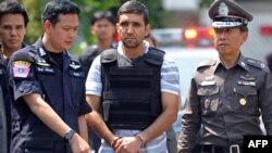 Thai police officers with detainee Mohammad Kharzei (center), one of three Iranian suspects held in a bomb investigation.