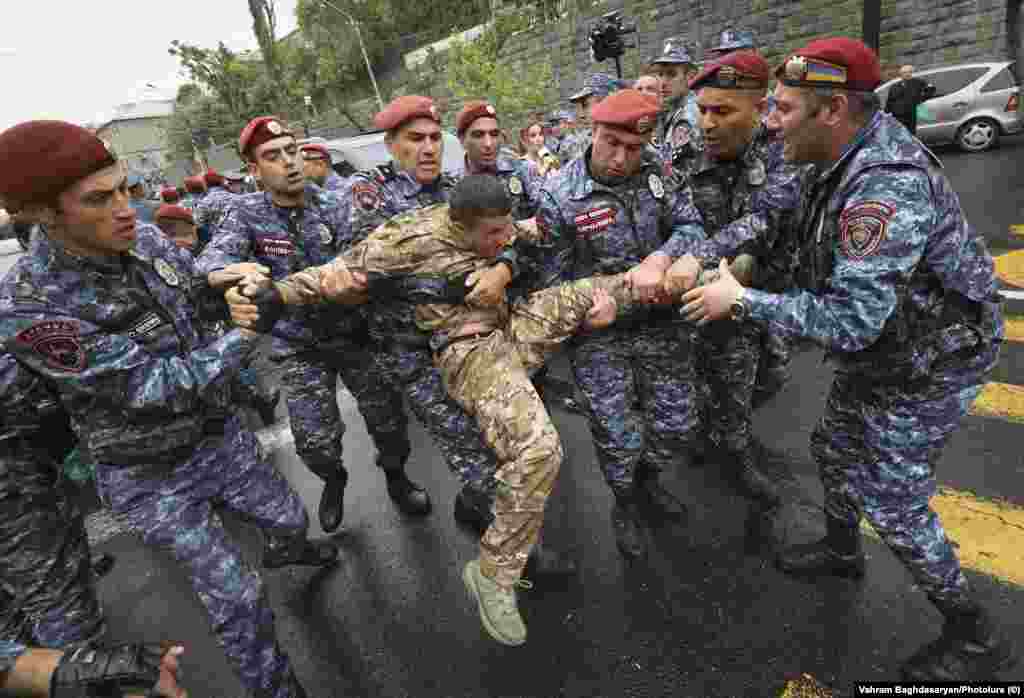 A man in military clothing grapples with police in Yerevan on May 2. Yerevan residents that RFE/RL's Armenian Service spoke to on May 3 expressed mixed feelings about the unrest, with one saying, "In democratic countries, governments are formed through elections. Period."