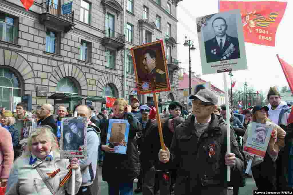 Участник акции "Бессмертный полк" в Петербурге с изображением своего родственника в одной руке и фотографией Иосифа Сталина в другой 