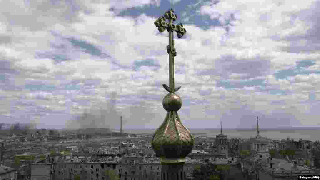 A cross from a church is seen against the backdrop of ongoing Russian shelling of the Azovstal steelworks on May 10. 