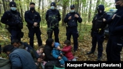 Иракские мигранты в окружении пограничников и полицейских на белорусско-польской границе