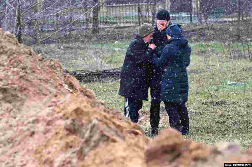 Люди плачуть біля одного із масових захоронень жертв російських військових. Буча, 3 квітня 2022 року. За повідомленням офіційного Києва, 175 загиблих людей знайшли у Бучі у різних місцях масових захоронень й катівнях 