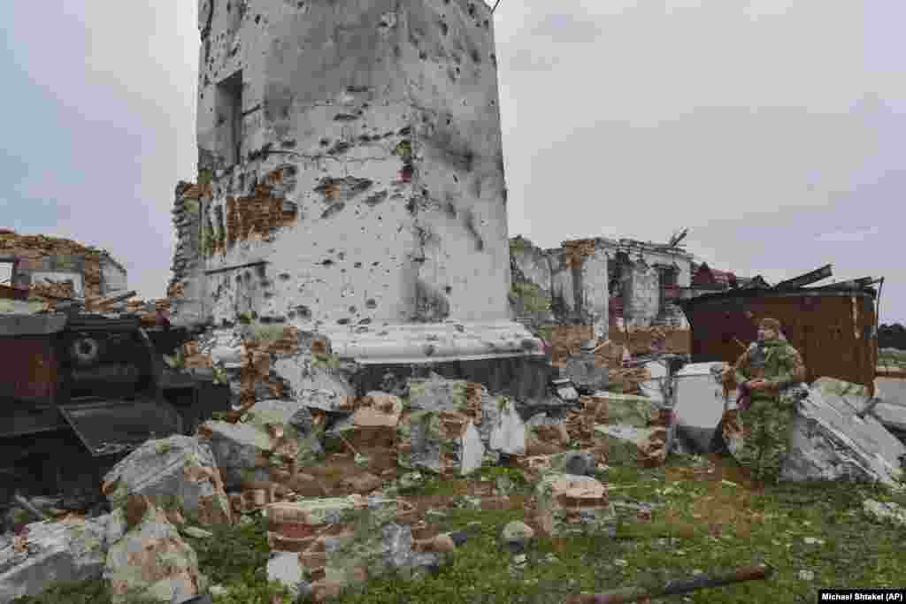 Украинский солдат у основания поврежденного 180-летнего маяка на Змеином острове. На фотографиях 2009 года видно здание вокруг этого маяка, которое было разрушено во время боев за остров.  