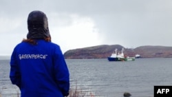 A Greenpeace activist looks at the "Arctic Sunrise" protest ship moored next to a Russian Coast Guard vessel near Murmansk.