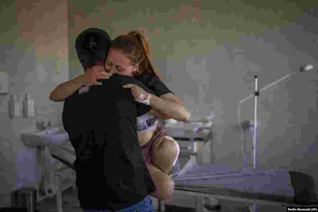 23-летнюю Оксану Баландину несет ее муж Виктор в больнице во Львове 13 мая 2022 года. Оксана потеряла обе ноги и четыре пальца на левой руке, когда возле ее дома разорвался российский снаряд. «Произошел взрыв. Мои ноги будто провалились в пустоту сразу после этого. Я попыталась осмотреться и увидела, что ног больше нет — только кости, плоть и кровь», — вспоминала она.