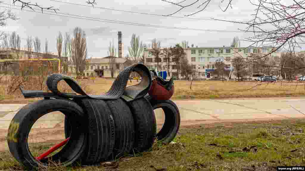 «Мотоцикл» из автомобильных шин на фоне производственных корпусов «Брома» (слева) и четырехэтажки межрайонной налоговой инспекции