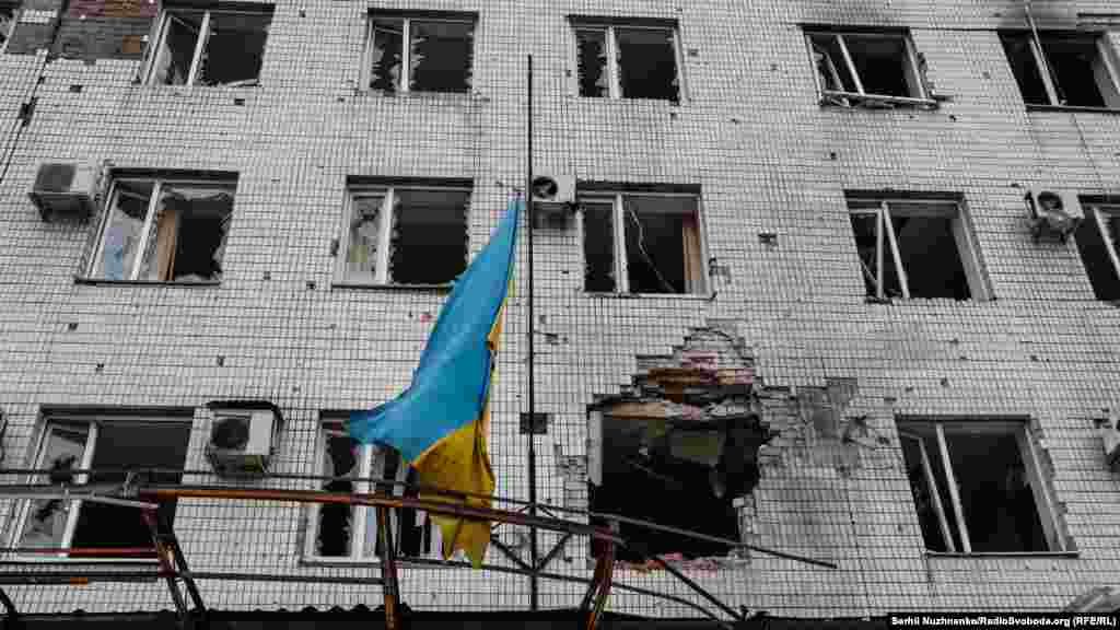 Прапор України на обстріляній цивільній будівлі у центрі Мар'їнки. Донбас, серединіа  квітня 2022 року. Російські війська, покинувши під тиском ЗСУ північ України, посилили атаки на Донбасі.  Боротьба за український прапор над визнаними світом українськими землями – триває