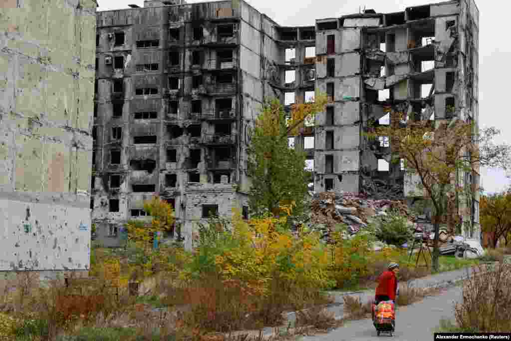 Женщина идет мимо полностью разрушенных российскими бомбардировками и не пригодных к жизни зданий в Мариуполе.  