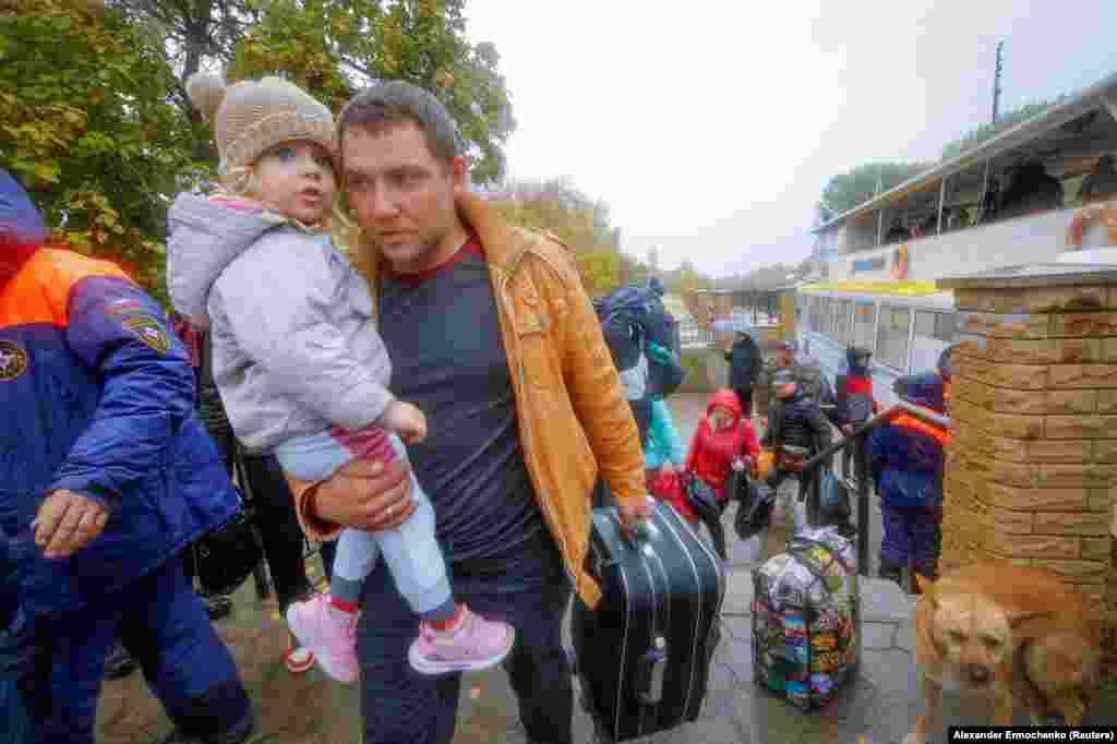 Мирные жители, эвакуированные из подконтрольного России города Херсона, идут от парома к автобусу  
