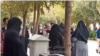 تصویری از درگیری که فرد روحانی با عصا به زن معترض حمله میکند
