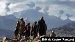 Anti-Taliban Afghan fighters watch several explosions from U.S. bombings in the Tora Bora Mountains of Afghanistan on December 16, 2001.