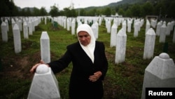 A Bosnian woman stands by the graves of her two sons, who were among some 8,000 men and boys massacred by Bosnian Serb forces in Srebrenica in 1995.