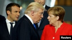 U.S. President Donald Trump (center) walks past French President Emmanuel Macron (left) and German Chancellor Angela Merkel (right) while getting into position for a group photo during a NATO summit in Brussels last May.