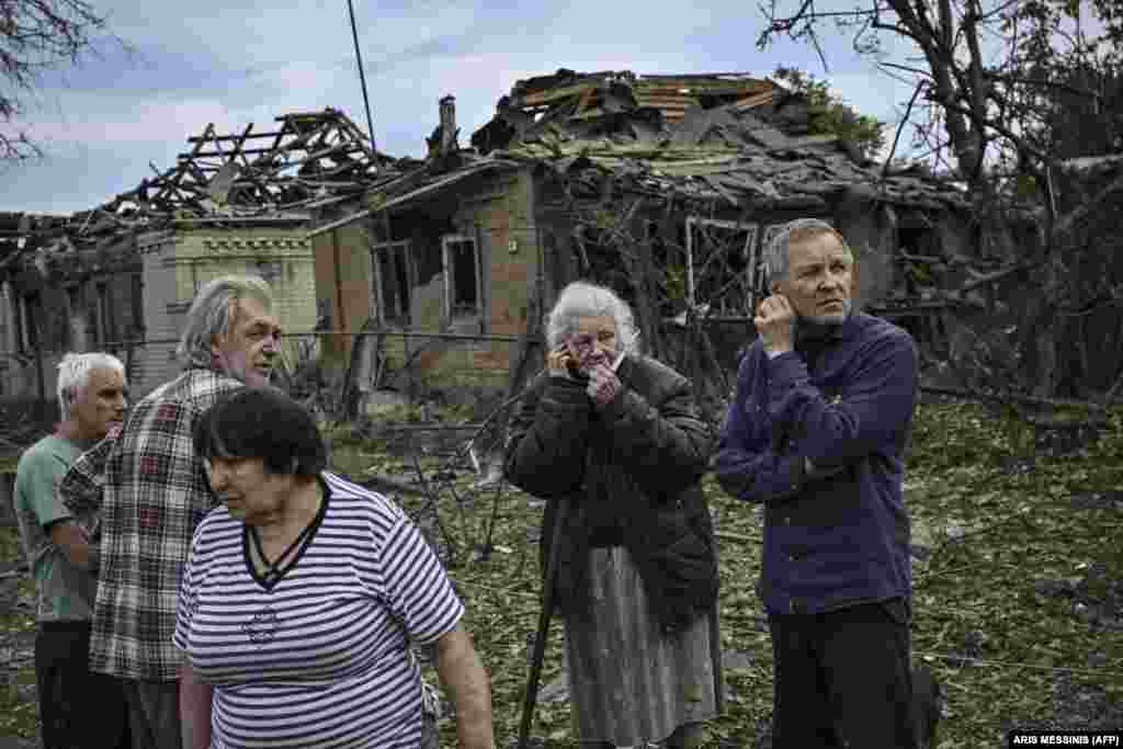 Местные жители собрались на улице после того, как в результате ракетного удара погибла пожилая женщина  