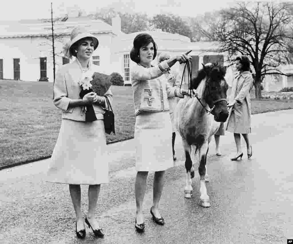 U.S. first lady Jacqueline Kennedy gives a guided tour of the White House grounds to Empress Farah in Washington in April 1962. Kennedy leads her daughter Caroline's pony, Macaroni, which had been nuzzling the empress, attracted by the daffodils she was carrying. In the background is the first lady's press secretary, Pamela Turnure. 