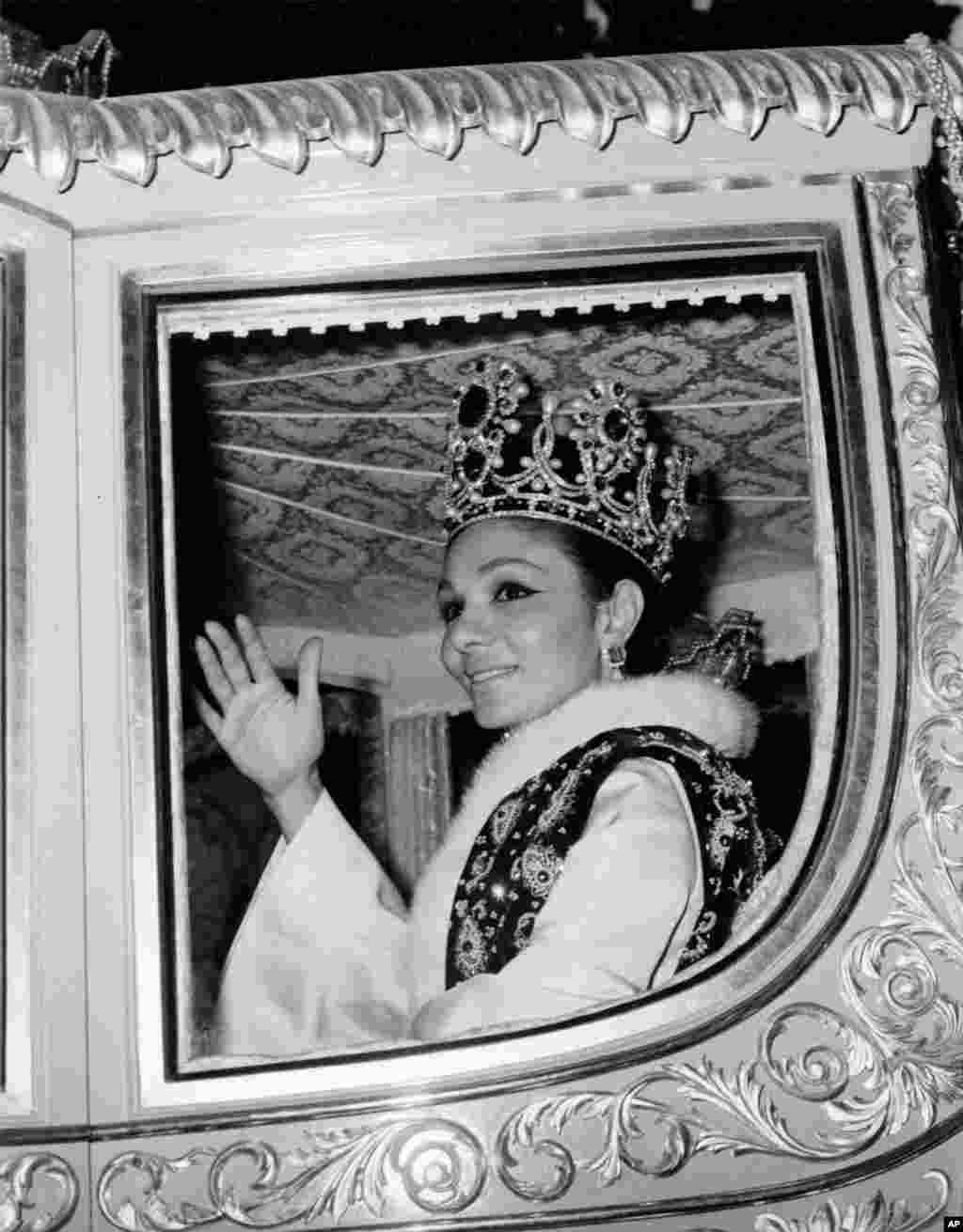 Empress Farah, wife of the shah of Iran, is pictured wearing her crown as she waves to crowds while driving through the streets of Tehran following their coronation ceremony on October 26, 1967. 