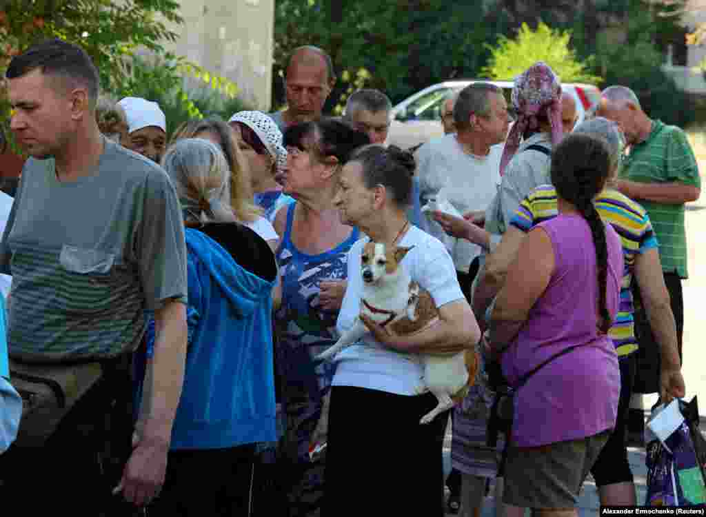 Local residents gather to receive food distributed by volunteers. The United Nations Office For the Coordination of Humanitarian Affairs (OCHA) called the situation in Syevyerodonetsk "dire" as humanitarian assistance is restricted, if not impossible.