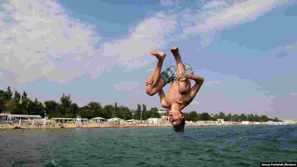 Ныряльщик в Евпатории прыгает с пирса в море 