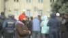 Женщина идет мимо участников протестов, начавшихся в Кыргызстане после парламентских выборов. Бишкек, 10 октября 2020 года.