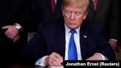 U.S. -- U.S. President Donald Trump signs a memorandum on intellectual property tariffs on high-tech goods from China, at the White House in Washington, U.S. March 22, 2018.