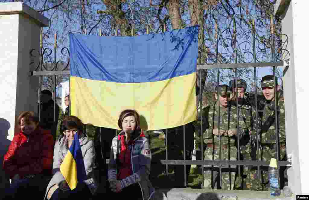 У селищі Любимівка українські військовослужбовці збираються на території військової частини. Їхні родичі сидять біля паркану, щоб не допустити збройних зіткнень, 3 березня 2014 року  