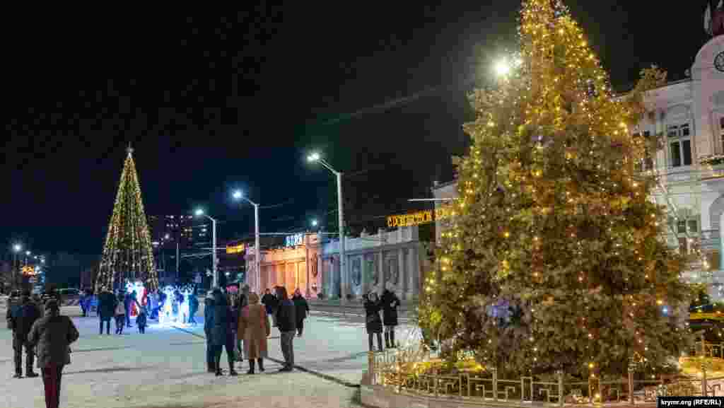 Евпатория. В этом году на Театральной площади установили искусственную главную городскую елку высотой 11 метров. Прежде такой роли удостаивалась живая, растущая, которую тоже украсили (справа).