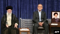 Sitting next to a portrait of late Iranian President Ebrahim Raisi, Masud Pezeshkian attends a ceremony for his presidential endorsement by Supreme Leader Ayatollah Ali Khamenei (left) in Tehran on July 28.