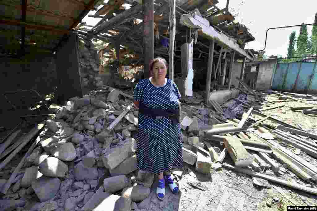 A woman stands in front of her damaged home in Azerbaijan's northern Tovuz region on July 16 after cross-border fighting resumed between Armenian and Azerbaijani forces.