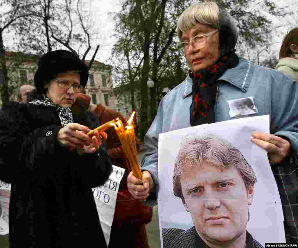 Women hold a poster of Litvinenko and light candles during a Moscow memorial on November 22, 2008. 