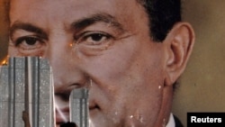 An antigovernment protester defaces a picture of President Hosni Mubarak in Alexandria