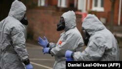 Military personnel wearing protective coveralls work to remove vehicles from a cordoned off area in Salisbury where a former Russian spy and his daughter were found poisoned last week.