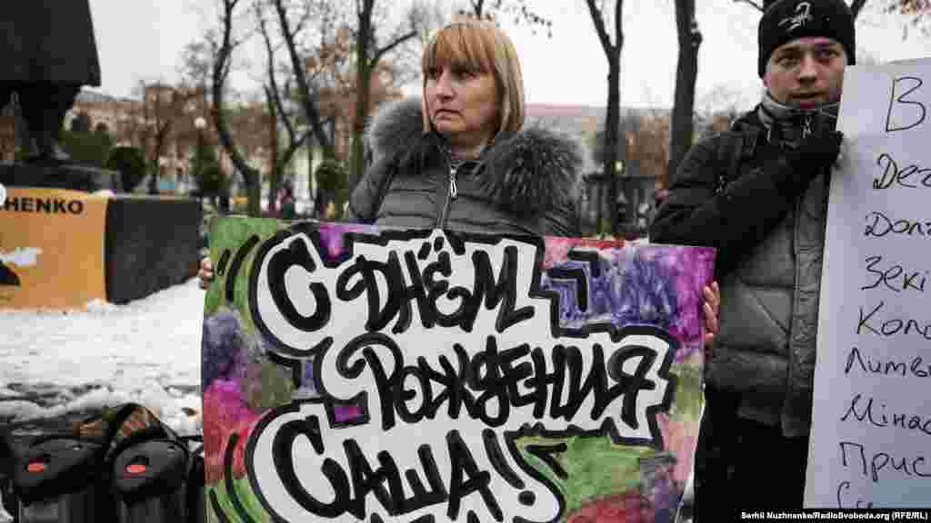 Мама Александра Лариса Кольченко держит плакат «С днем рождения, Саша»