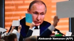 Russian President Vladimir Putin is seen on a large screen as he speaks during his annual press conference in Moscow on December 19.