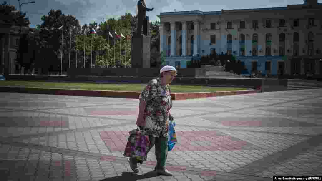 Женщина идет с покупками по площади Ленина 
