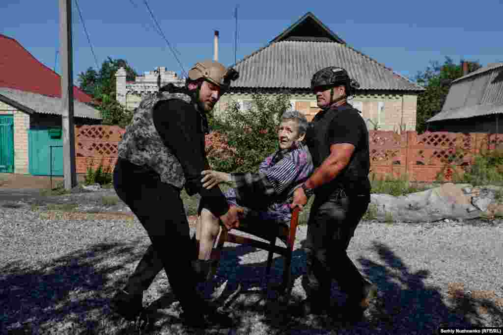O femeie este evacuată din Novohrodivka, regiunea Donețk, în august 2024. Trupele ruse au ocupat orașul la 20 de zile după ce a fost făcută această fotografie. Bărbatul din dreapta este Owen, un voluntar din Noua Zeelandă. Fost medic militar, el a venit în Ucraina pentru a ajuta la salvarea oamenilor. 