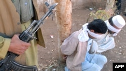 An Islamic militant guards two criminals before their public execution in Khyber tribal region