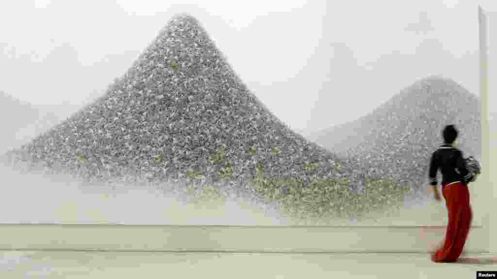A visitor walks past "Ash Colour Mountains," an acrylic on canvas by Japanese artist Makoto Aida. 