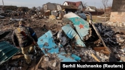 Военнослужащий ВСУ осматривает остатки российского боевого самолета Су-34 в жилом районе Чернигова. 6 апреля 2022 года